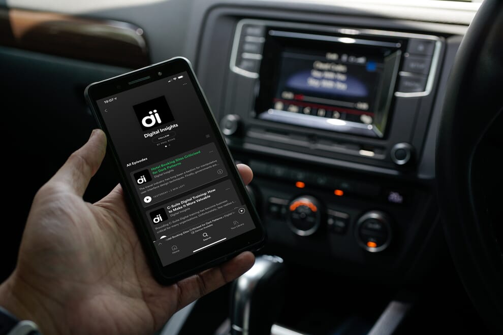 Person listening to podcast in car to avoid information overload.